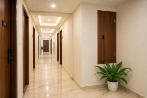 a hallway with white walls and a plant in a pot at K Grandeur Hotels- South Railway Station in Cochin