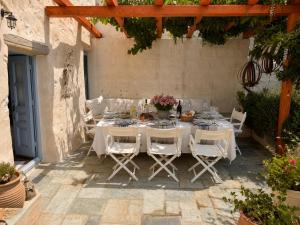 a white table with white chairs and flowers on it at Chora Heritage Residence by Belle-Stay in Patmos +32 photos