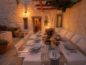 a long table with plates and silverware on it at Chora Heritage Residence by Belle-Stay in Patmos