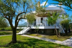 a white house with a balcony and a tree at Olive Garden Vila in Karianí