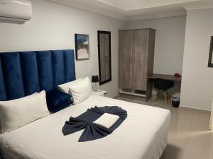 a bedroom with a large white bed with a blue headboard at Executive Suites and Spa in Letlhakawe