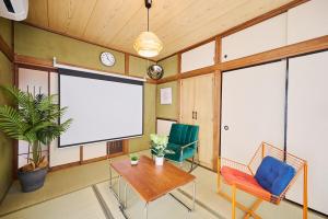 a room with two chairs and a table and a projection screen at Kokonimo Kawagoesenba in Kawagoe