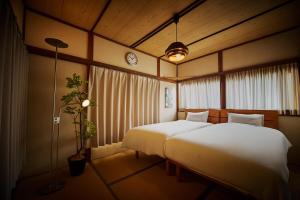 a bedroom with two beds and a clock on the wall at Kokonimo Kawagoesenba in Kawagoe