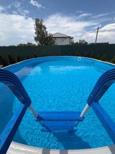 a blue swimming pool with two chairs in it at Villa Menorca in Chornomorsk