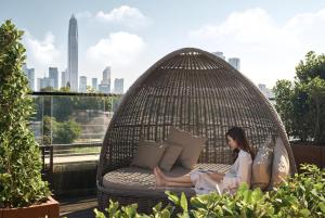 a woman sitting in a wicker chair on a balcony at JW Marriott Hotel Shenzhen in Shenzhen