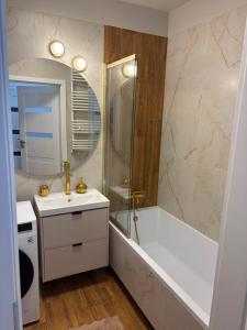 a bathroom with a tub and a sink and a shower at PikApart in Olsztyn +27 photos