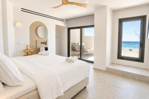 a white bedroom with a large bed and a large window at enplomare in Plomari