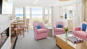 a living room with pink chairs and a table and the ocean at The Tides Beach Club in Kennebunkport