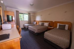 a hotel room with two beds and a desk at Narellan Motor Inn in Narellan