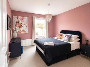 a bedroom with a large bed with pink walls at The Stables in Market Rasen