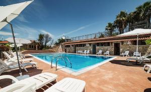 a swimming pool with white chairs and a house at Il Falco del Cilento in Torchiara
