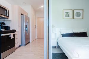 a bedroom with a white bed and a kitchen at Joinery North in Charlotte