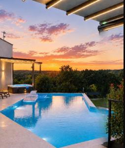 a swimming pool with a sunset in the background at Residence Villa Manuela - Pool & Jacuzzi - Batlug in Batlug