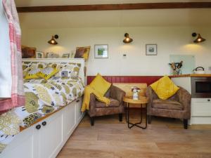 a bedroom with a bed and two chairs at The Herdsman Luxury Shepherds Hut in Barnoldswick