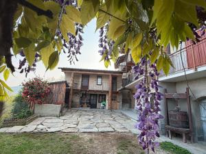 an exterior view of a house with purple flowers at El Torch di Long Elisa in San Garmano Chisone +8 photos