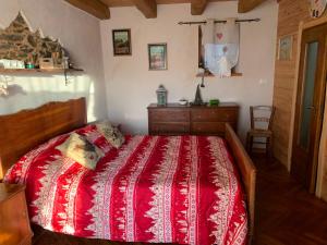 a bedroom with a red bed and a dresser at El Torch di Long Elisa in San Garmano Chisone