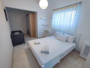 a bedroom with a white bed with flip flops on it at Linovrochi holiday house with private pool in Lefkandi Chalkidas