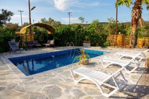 a swimming pool with two white lounge chairs next to it at Linovrochi holiday house with private pool in Lefkandi Chalkidas