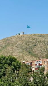 a building on top of a hill with a flag on it at House on the mountain in Ustʼ-Kamenogorsk