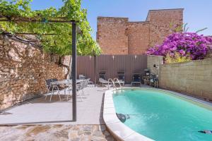 a swimming pool with a table and chairs next to a building at Le Clos Mazerolles in Cruzy