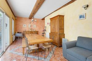 a dining room with a wooden table and a couch at Le Clos Mazerolles in Cruzy