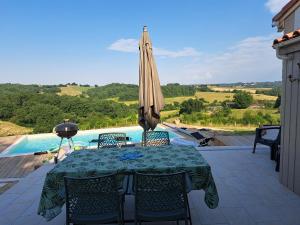 a patio with a table and an umbrella at Lôu cayrou in Beaumarches