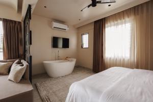 a bedroom with a white bed and a bath tub at Abhibha Suites Waterfront in Pune