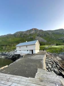 a white building with a mountain in the background at Skjellfjord cabin in Skjelfjord