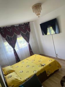 a bedroom with a yellow comforter and two windows at Apartament NEPTUN in Neptun