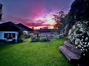 a park bench in a yard with a sunset at Ferienwohnungen Heissbauer in Wackersberg