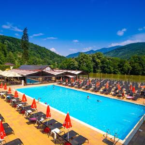 a large swimming pool with chairs and umbrellas at Olt view apartament in Călimăneşti