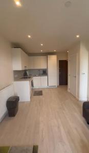 an empty living room with white cabinets and a wooden floor at Harrow Nest - 1Bedroom in Hatch End