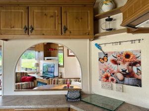 a kitchen with a living room with a cow painting on the wall at Cosalt Sea View 18 in Ardentinny