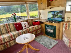 a living room with a couch and a television at Cosalt Sea View 18 in Ardentinny