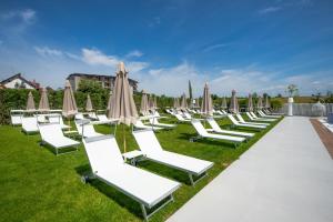 eine Reihe weißer Liegestühle mit Sonnenschirmen in der Unterkunft Glory Resort in Baile Felix