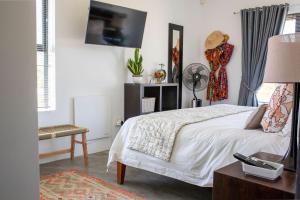 a bedroom with a bed and a tv on the wall at Stay At Friends in Bettyʼs Bay +55 photos