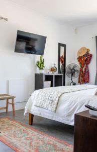 a bedroom with a bed and a tv on the wall at Stay At Friends in Bettyʼs Bay