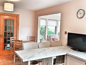 a living room with a table and a clock on the wall at Golf View, Cruden Bay in Cruden Bay