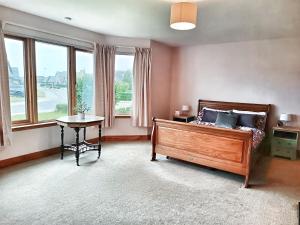 a bedroom with a bed and a table and windows at Golf View, Cruden Bay in Cruden Bay