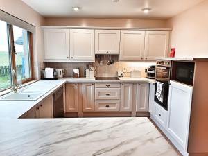 a kitchen with white cabinets and a large window at Golf View, Cruden Bay in Cruden Bay