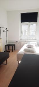 a white bedroom with a bed and a window at Private Room in a shared apartment in Odense