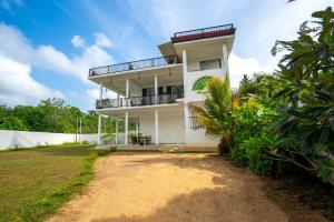 a white house with a balcony and a yard at Monara Villa in Dharga Town