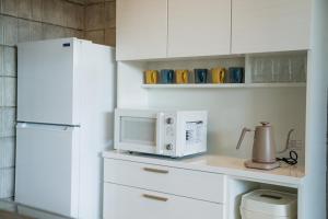 eine Küche mit einem weißen Kühlschrank und einer Mikrowelle in der Unterkunft vividテラス101 in Miyako-jima + 23 Fotos