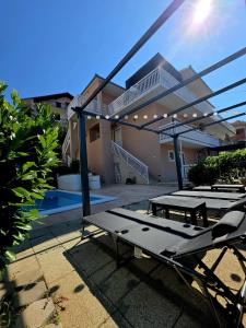 a patio with a table and picnic tables in front of a house at Beautiful Holiday Home "Villa Relax Oasis" in Trogir