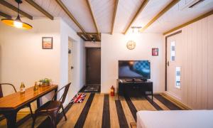 a living room with a table and a television at La Beaute Jeju Pension in Seogwipo