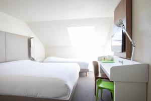 a hotel room with two beds and a desk and a window at Campanile Evry Ouest - Corbeil Essonnes in Corbeil-Essonnes