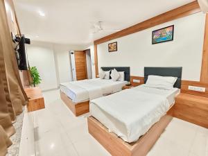 a bedroom with two beds and a flat screen tv at Hotel Royal Relax in Gandhinagar +17 photos