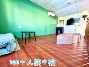 a living room with a table and a green wall at 蒲Going旅宿 in Xiaoliuqiu