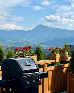 a grill sitting on top of a balcony with flowers at Villa Bergbliss in Bukovel