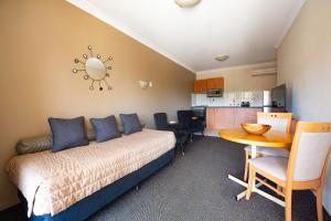a bedroom with a bed and a table and a kitchen at Narellan Motor Inn in Narellan